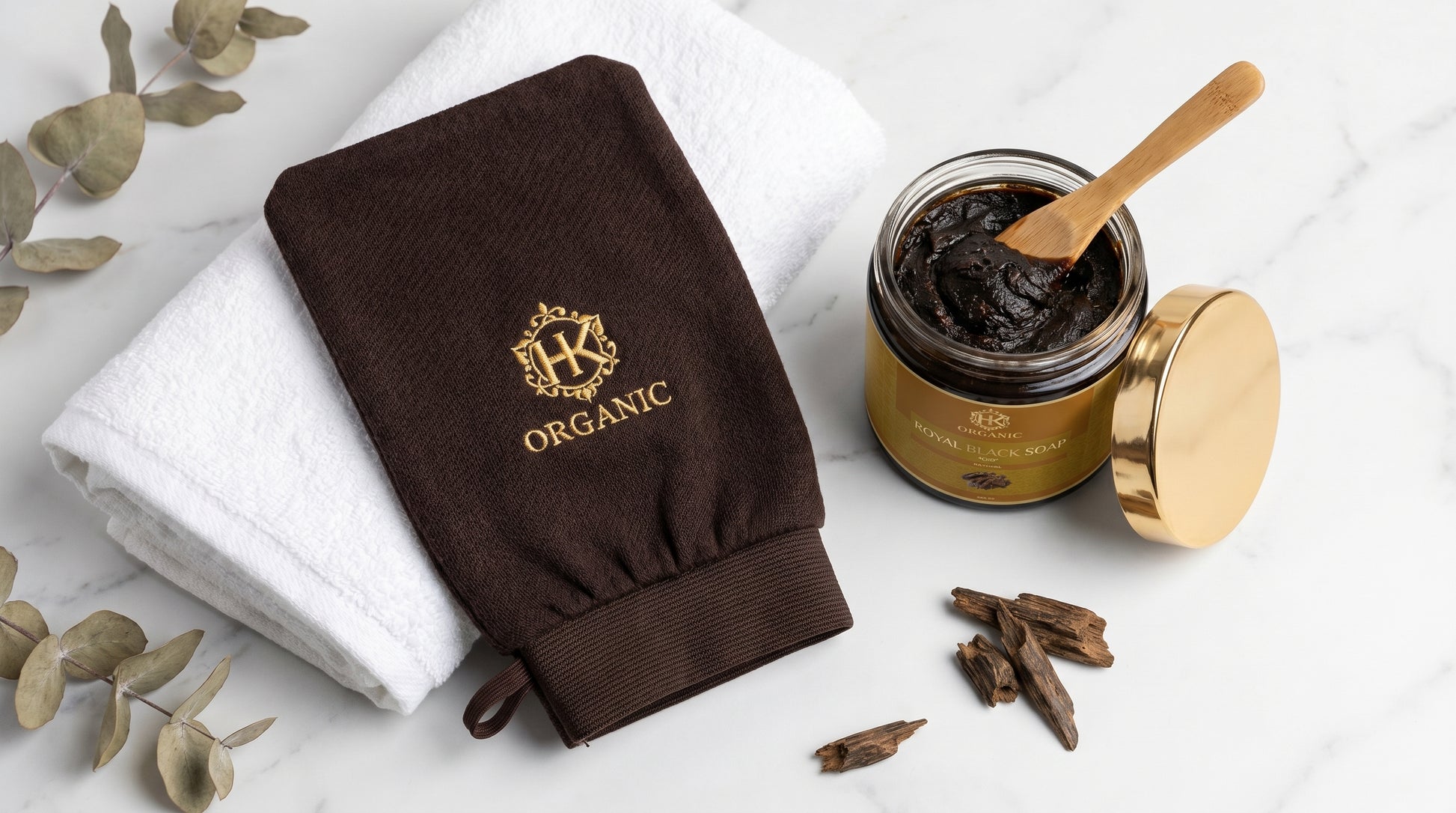Brown organic glove and jar of cream on a white background with eucalyptus leaves.