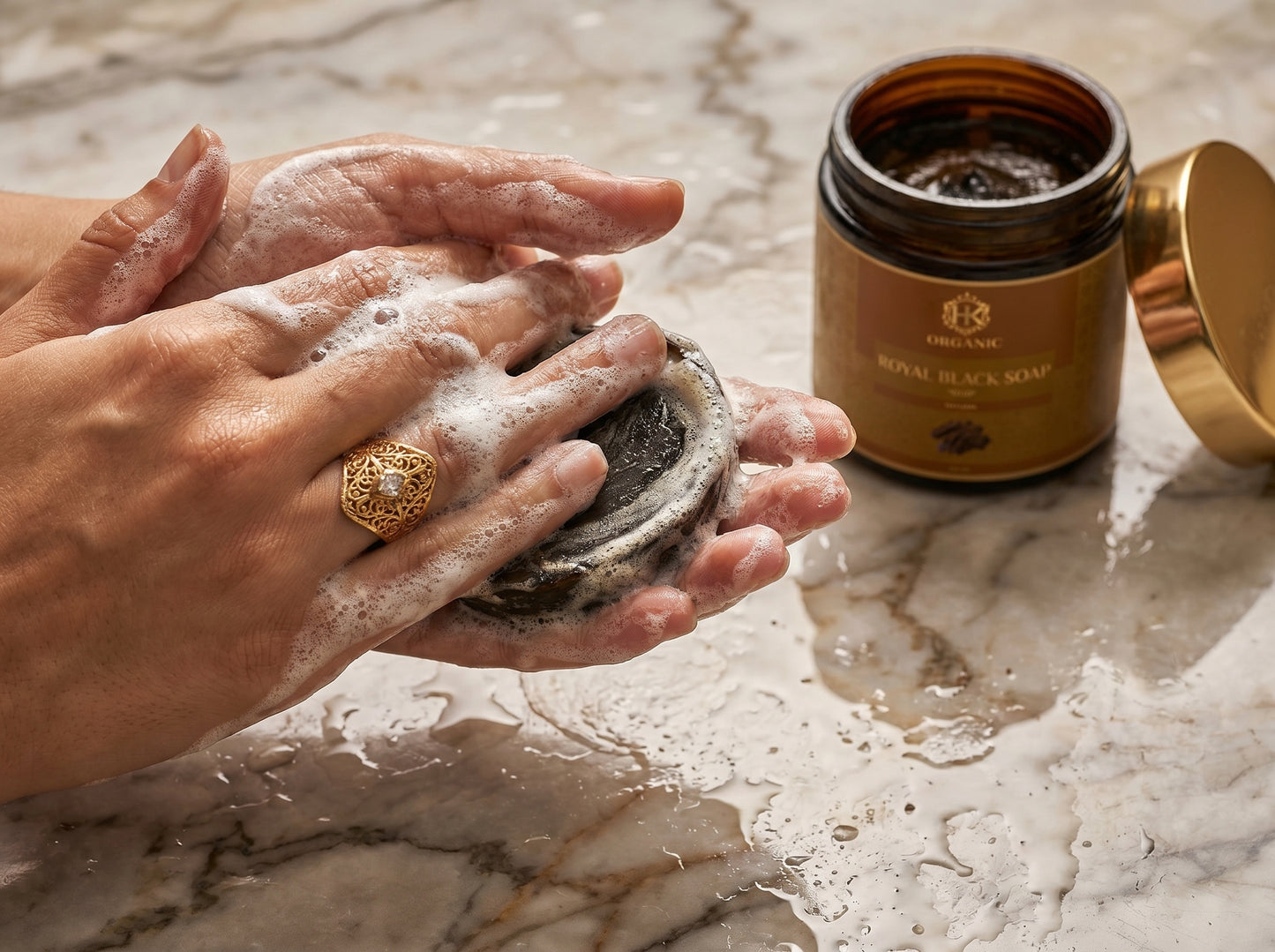 Person washing hands with soapy hands and a jar of soap on a marble surface