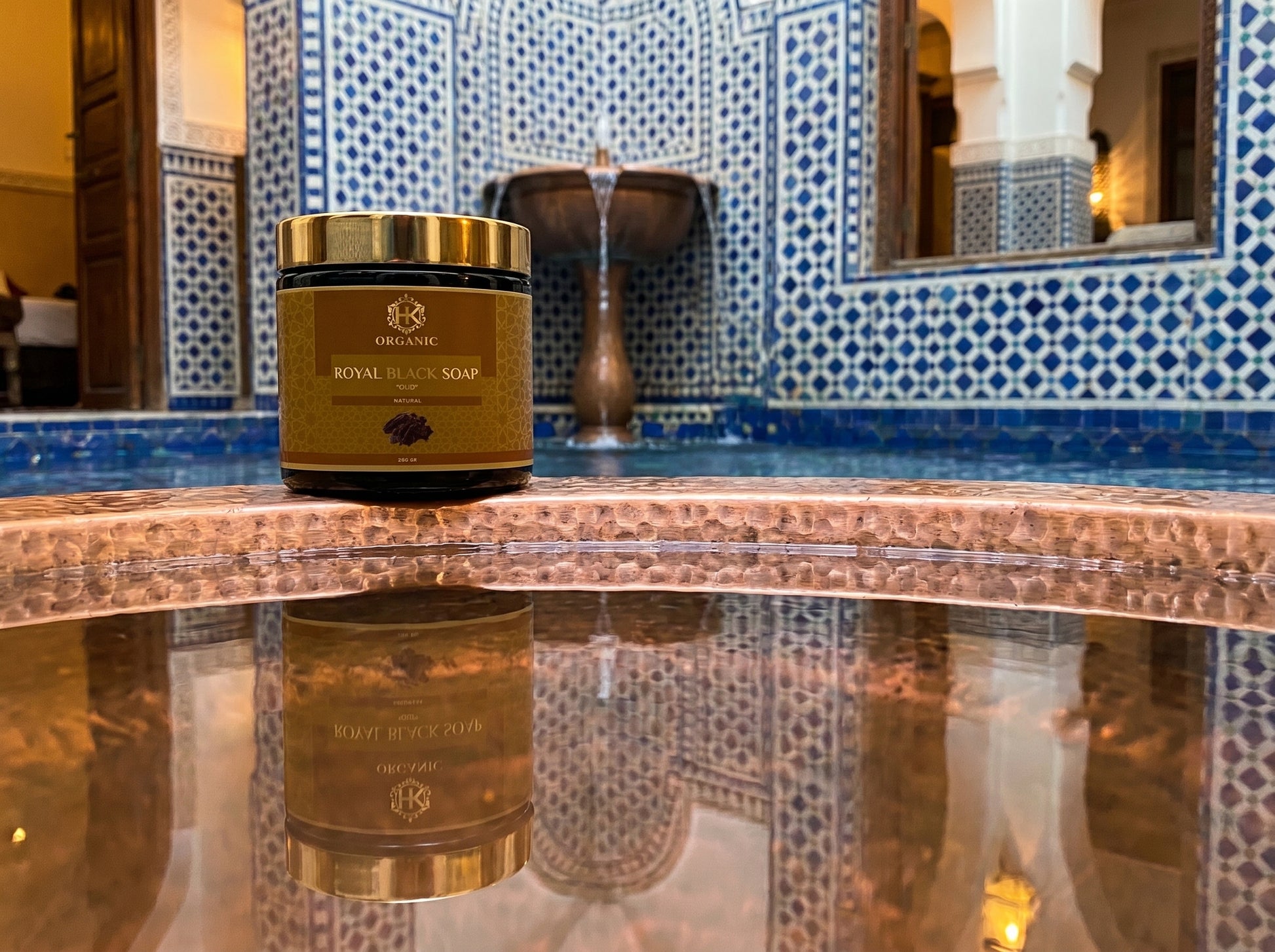 Jar of Royal Black Soap on a reflective surface with decorative tiles in the background