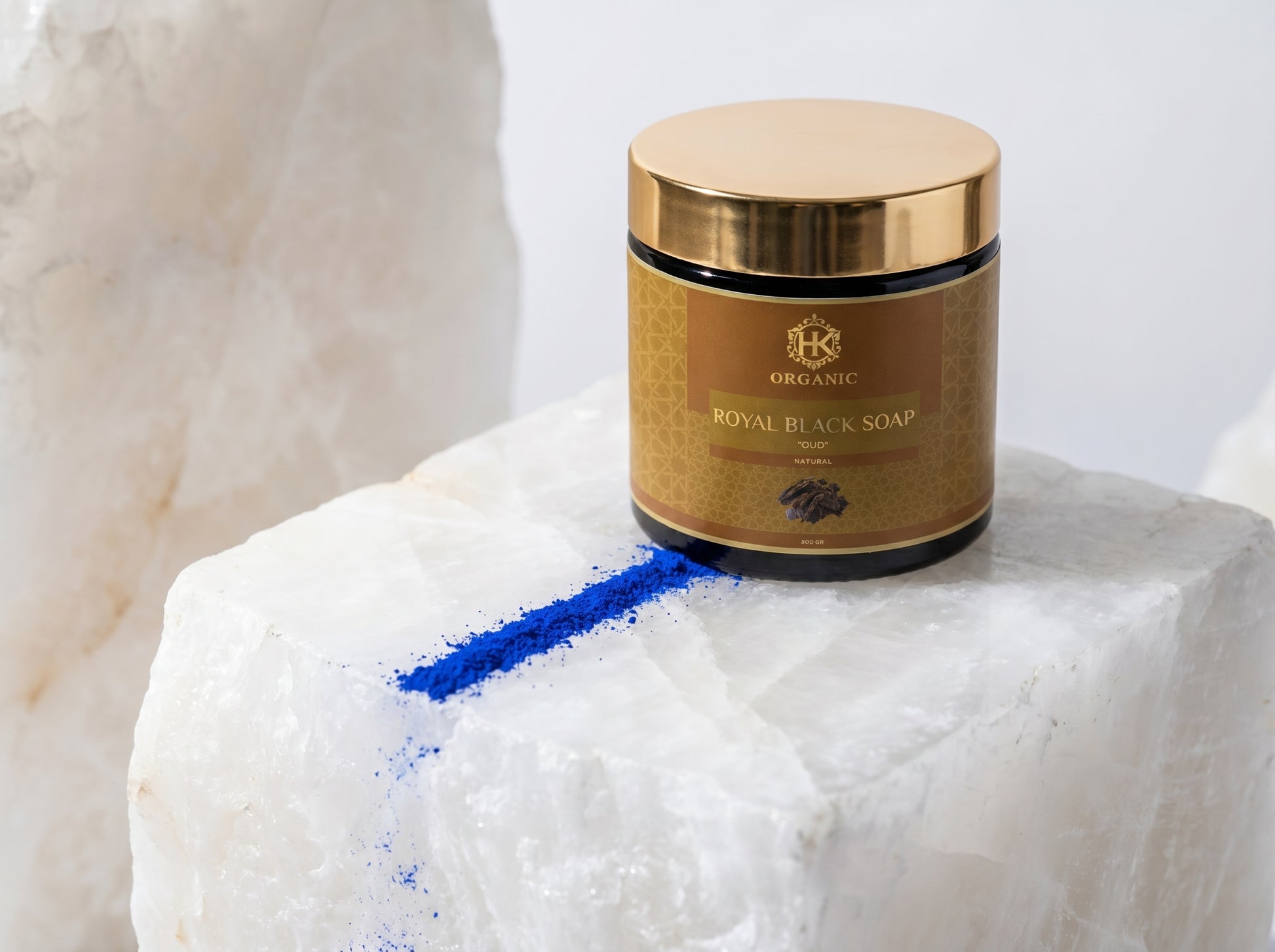Jar of Royal Black Soap on a marble surface with blue powder