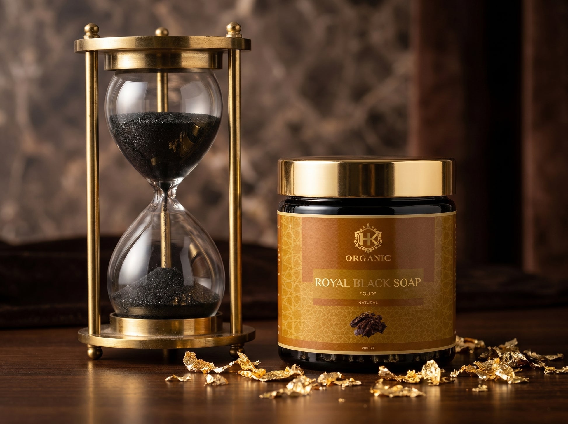 Jar of Royal Black Soap with gold lid next to an hourglass on a wooden surface.