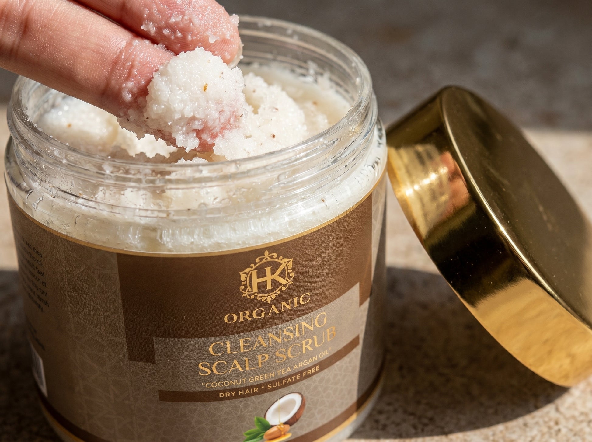 Jar of organic cleansing scalp scrub with a hand holding a scoop of the product.