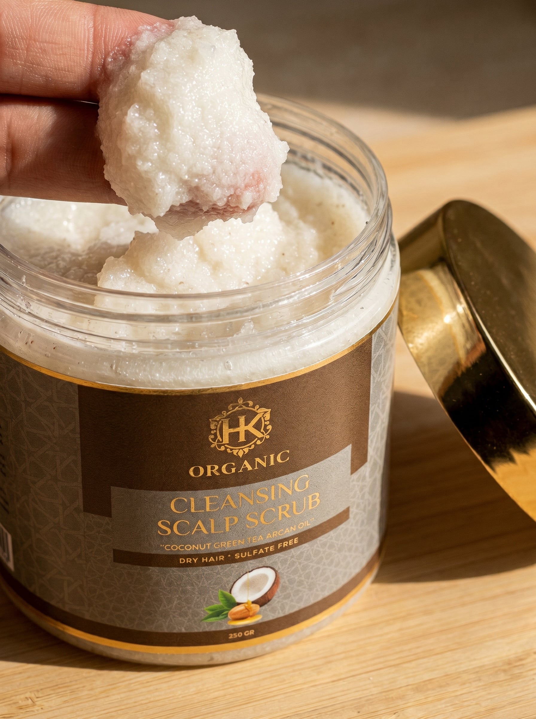 Jar of organic cleansing scalp scrub with a scoop of scrub on top, on a wooden surface.