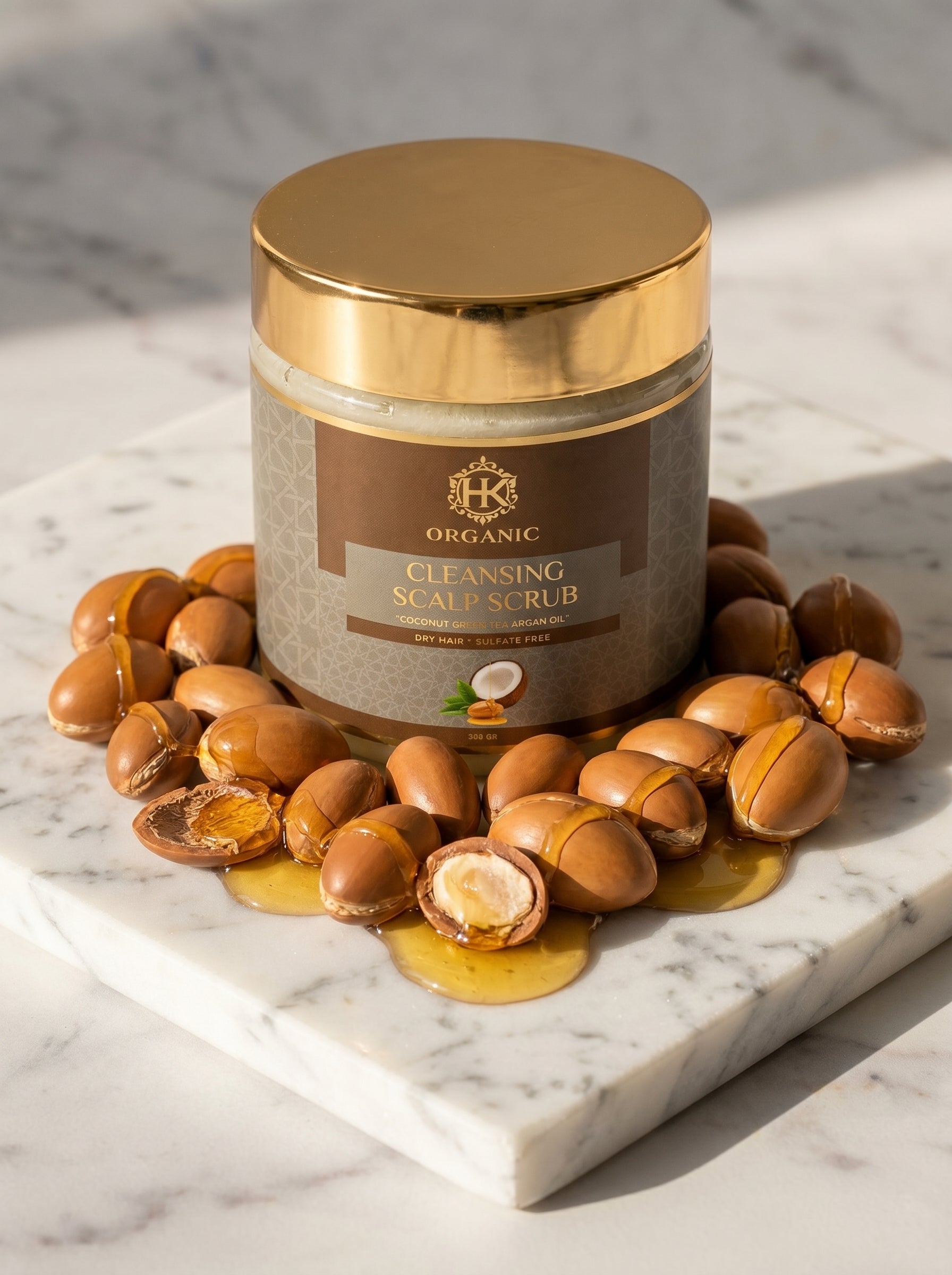 Jar of organic cleansing scalp scrub surrounded by argan seeds on a marble surface