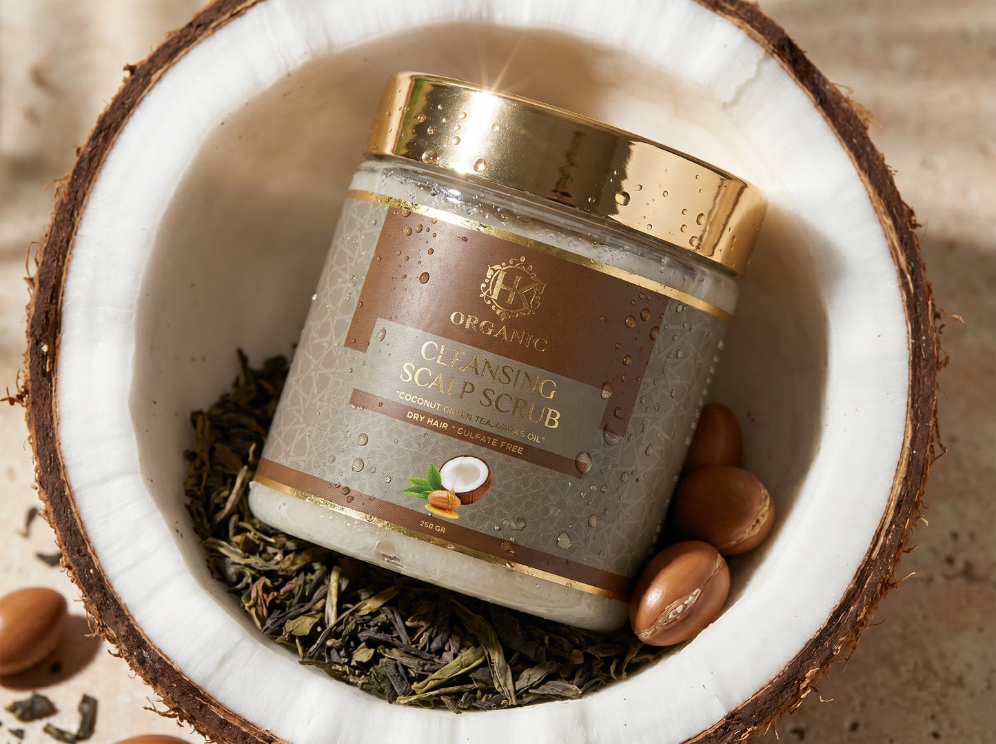 Jar of cleansing soap scrub with a gold lid inside a coconut shell with herbs and nuts.