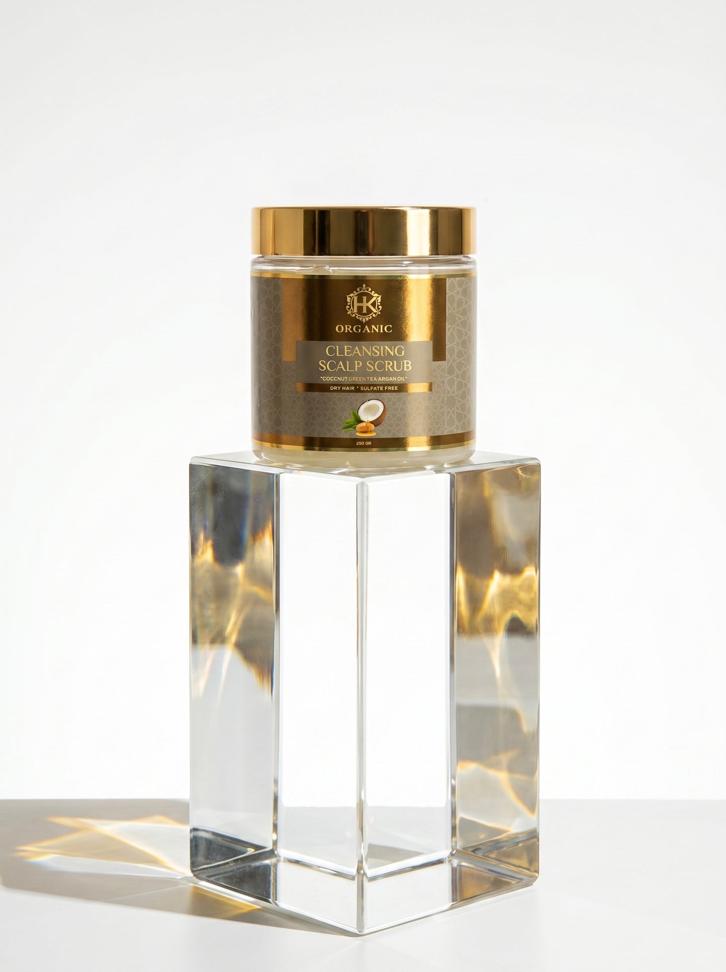 Gold jar of scalp scrub on a reflective surface with a white background