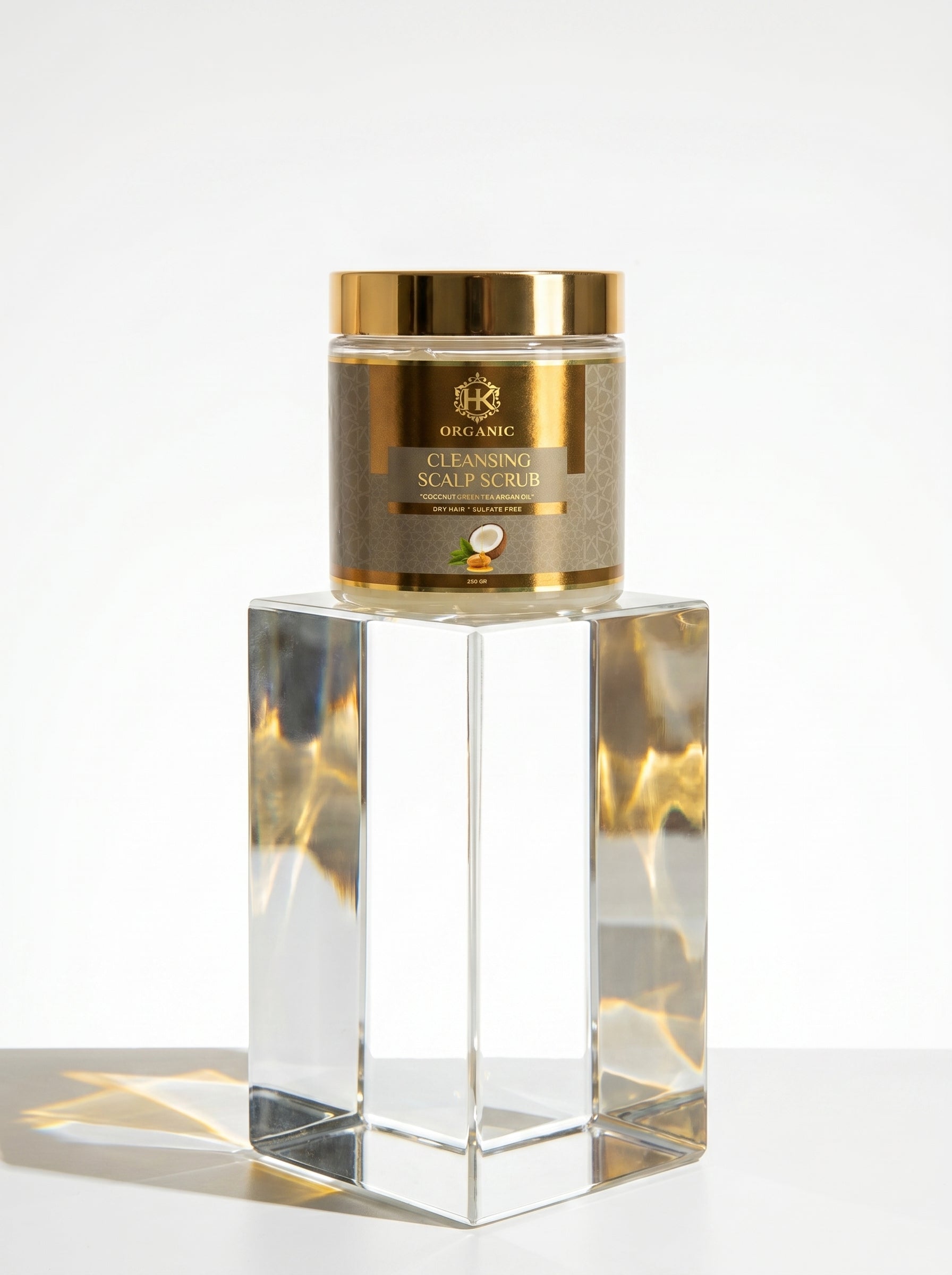 Gold jar of scalp scrub on a reflective surface with a white background