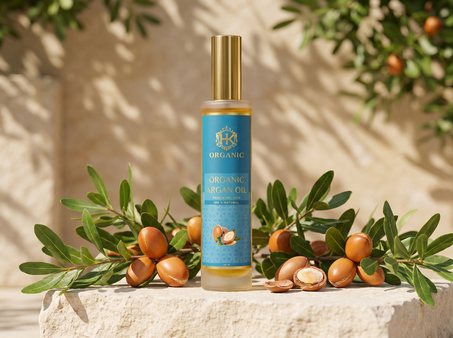 A bottle of Organic Argan Oil stands on a stone surface surrounded by argan branches and nuts, with a warm beige wall and leaf shadows in the background.