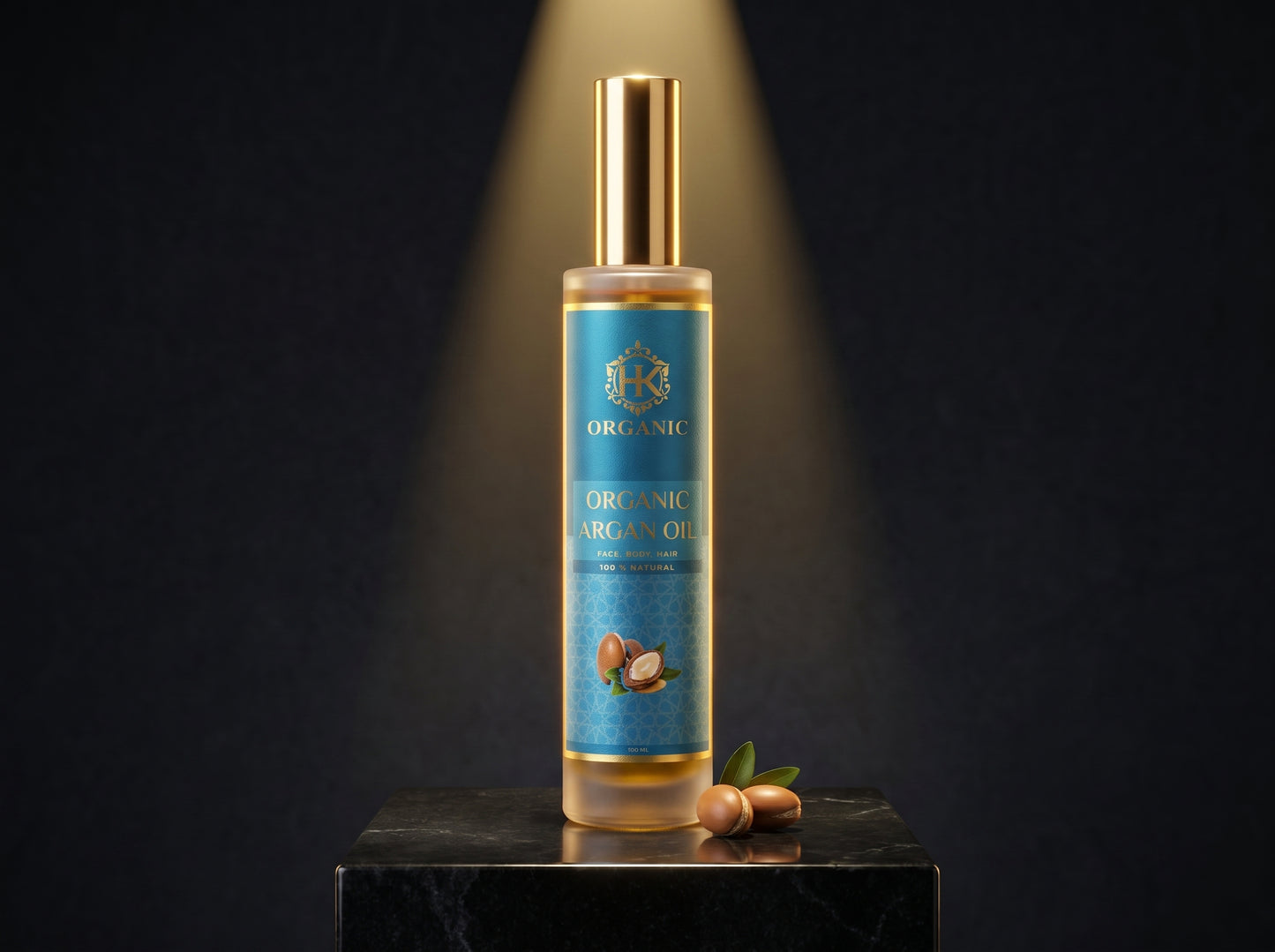 A bottle of Organic Argan Oil stands on a black marble pedestal against a dark background with a spotlight effect. The bottle has a blue label with gold lettering and a gold cap, with two argan nuts and a small green leaf resting beside the base.